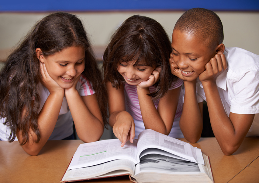 School kids, reading and happy in classroom with book, pointing Rainard giftedness